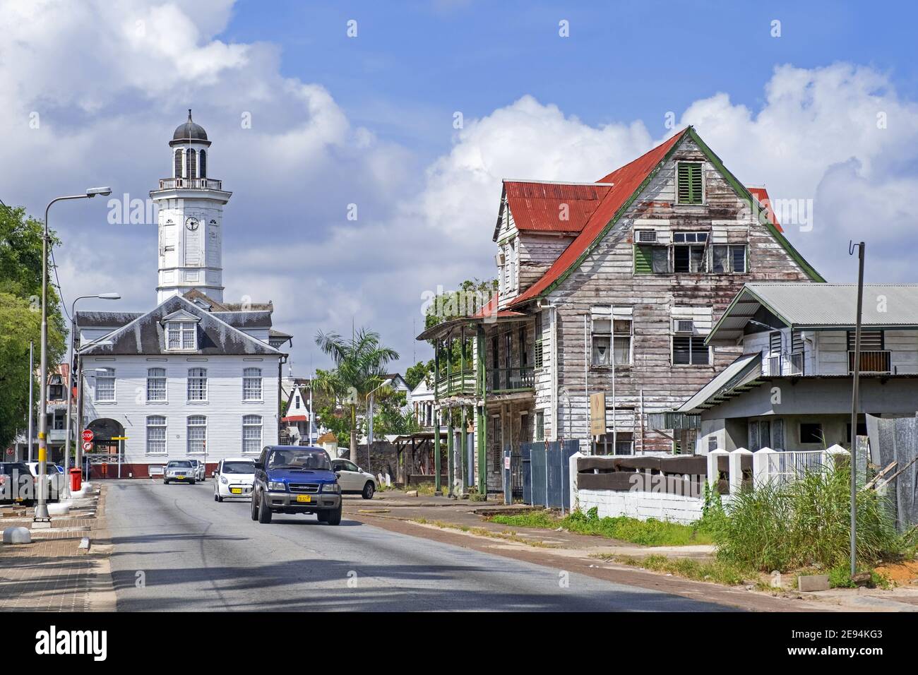 White wooden clock tower of the Ministry of Finance building and colonial houses in the city centre of Paramaribo, Suriname / Surinam Stock Photo