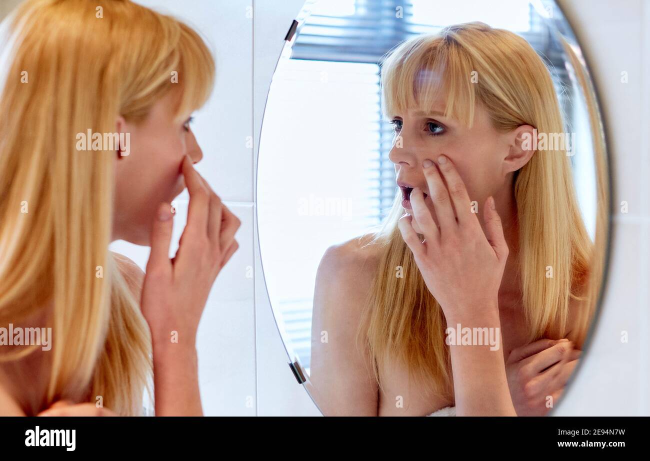 Woman looking at her eyes in a mirror Stock Photo
