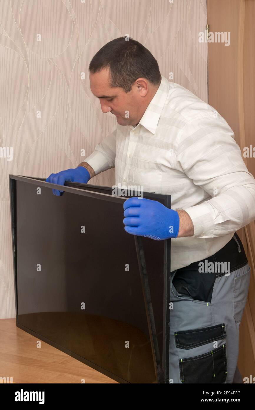 Home technician repairs LCD TV. Engineer removes monitor frame. Calling the master at home. Selective focus. Stock Photo