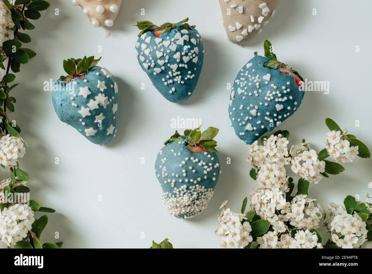 Step by step. Tasty Blue and white chocolate dipped strawberries with sugar sprinkles on a parchment paper. valentine´s day Stock Photo