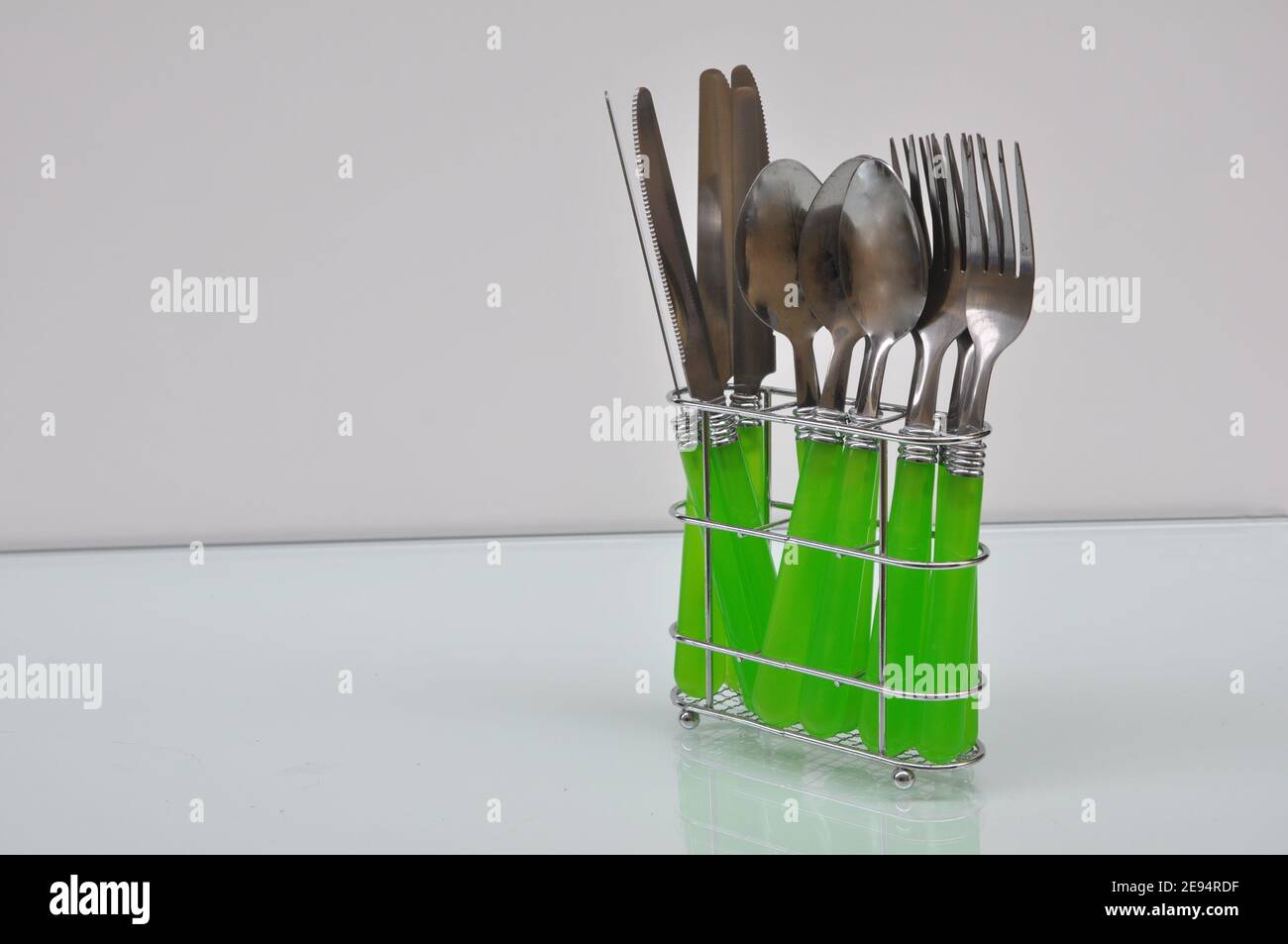 Aluminum support with green forks, knives and spoons on white background, in space copy, Brazil, South America Stock Photo