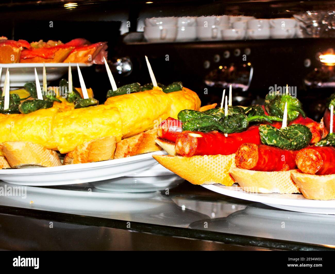 Spanish tapas of potato omelette and chorizo with fried peppers on top and bread base Stock Photo