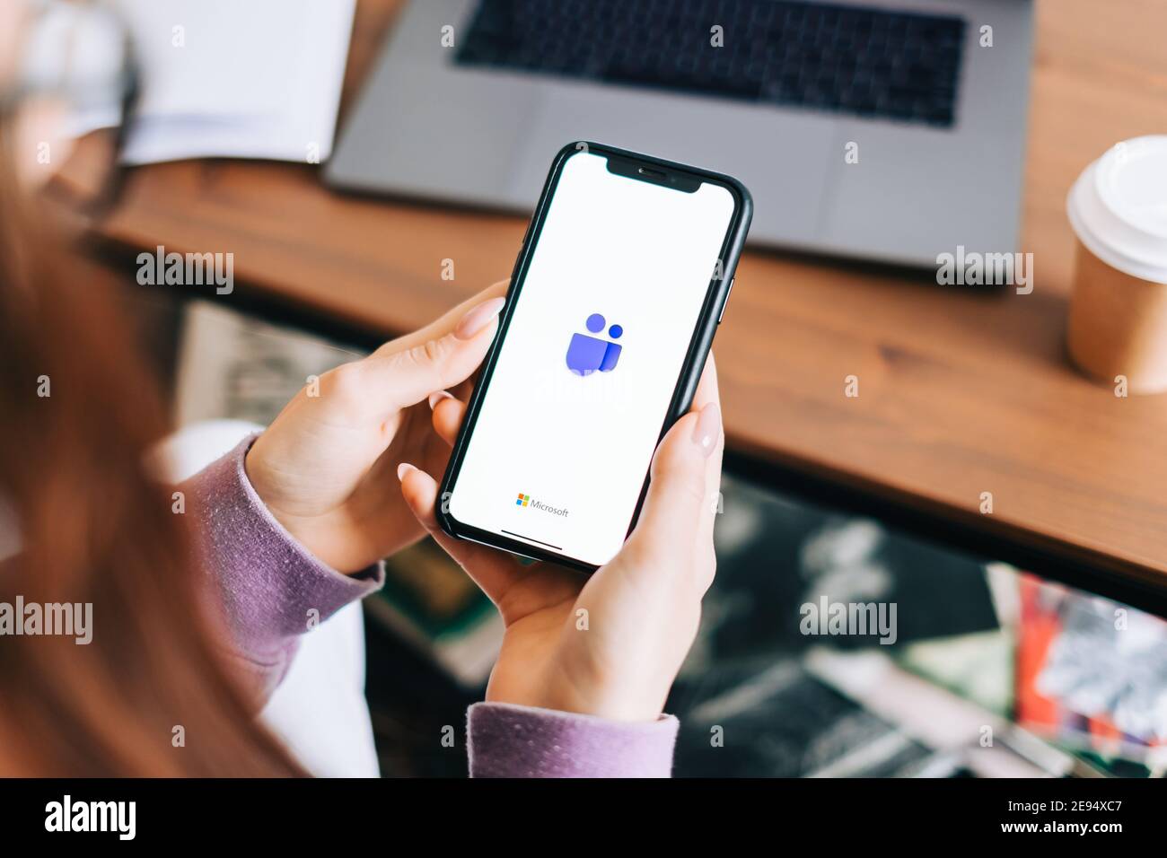 Hand holding iPhone with Microsoft Teams video call app logo on the