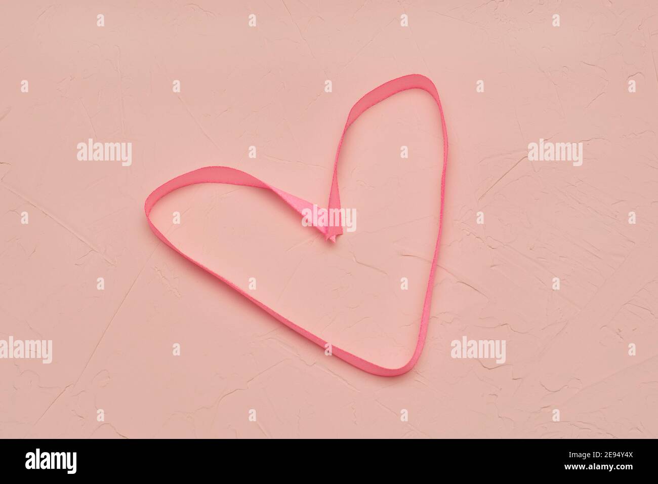 Silk fabric in shape of heart on pink background texture of concrete and plaster. Concept for Valentine's Day, love, wedding. Stock Photo