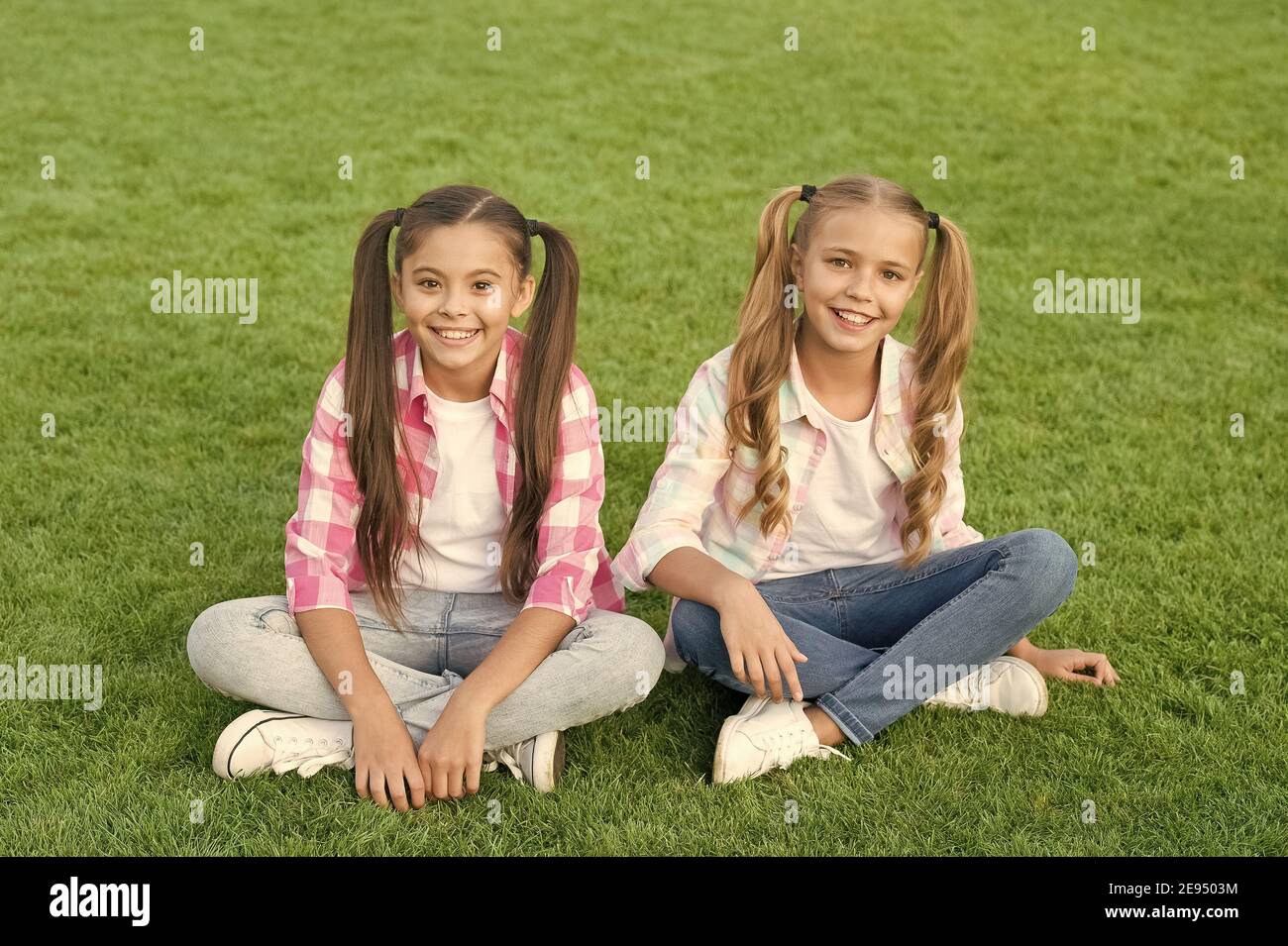 Children are future. Little children sit on green grass. Happy children have fun outdoors. Small children with fashion look. Casual style trend. Happy childhood. International childrens day. Stock Photo