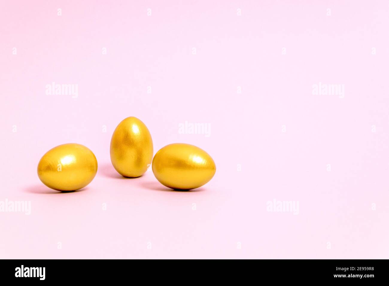 Three Easter eggs decorated with gold paint on a pink background. Concept for Easter, spring. Selective focus. Copy space. Stock Photo