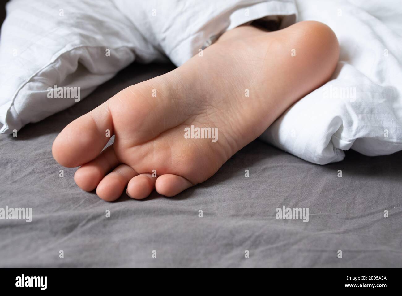 The foot of a sleeping boy sticking out from under the covers on the bed Stock Photo Alamy