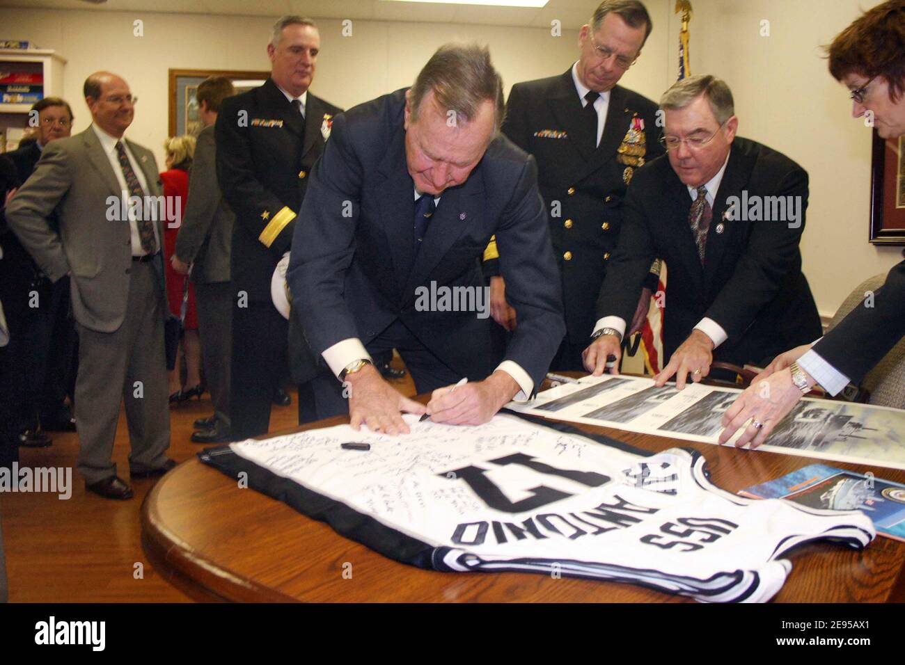 Former US President George Bush autographs a basketball jersey for the crew of USS San Antonio (LPD 17). Various artifacts were signed by visiting dignitaries, and will later be displayed aboard the ship, commemorating her commissioning in Ingleside, TX on January 14, 2006. Photo by USN via ABACAPRESS.COM Stock Photo