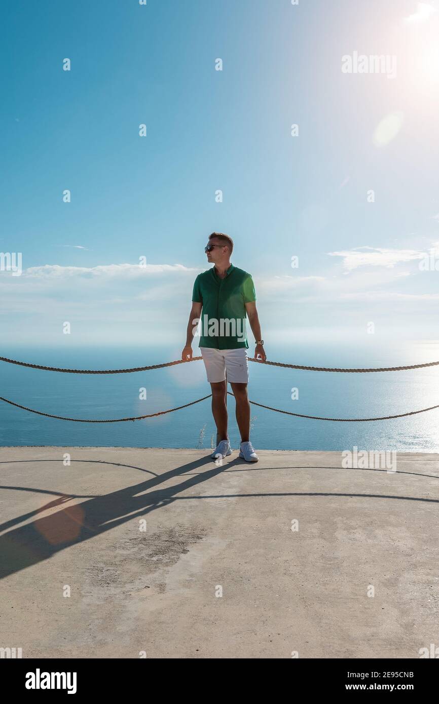 Happy guy in a green shirt on sea background. Stock Photo