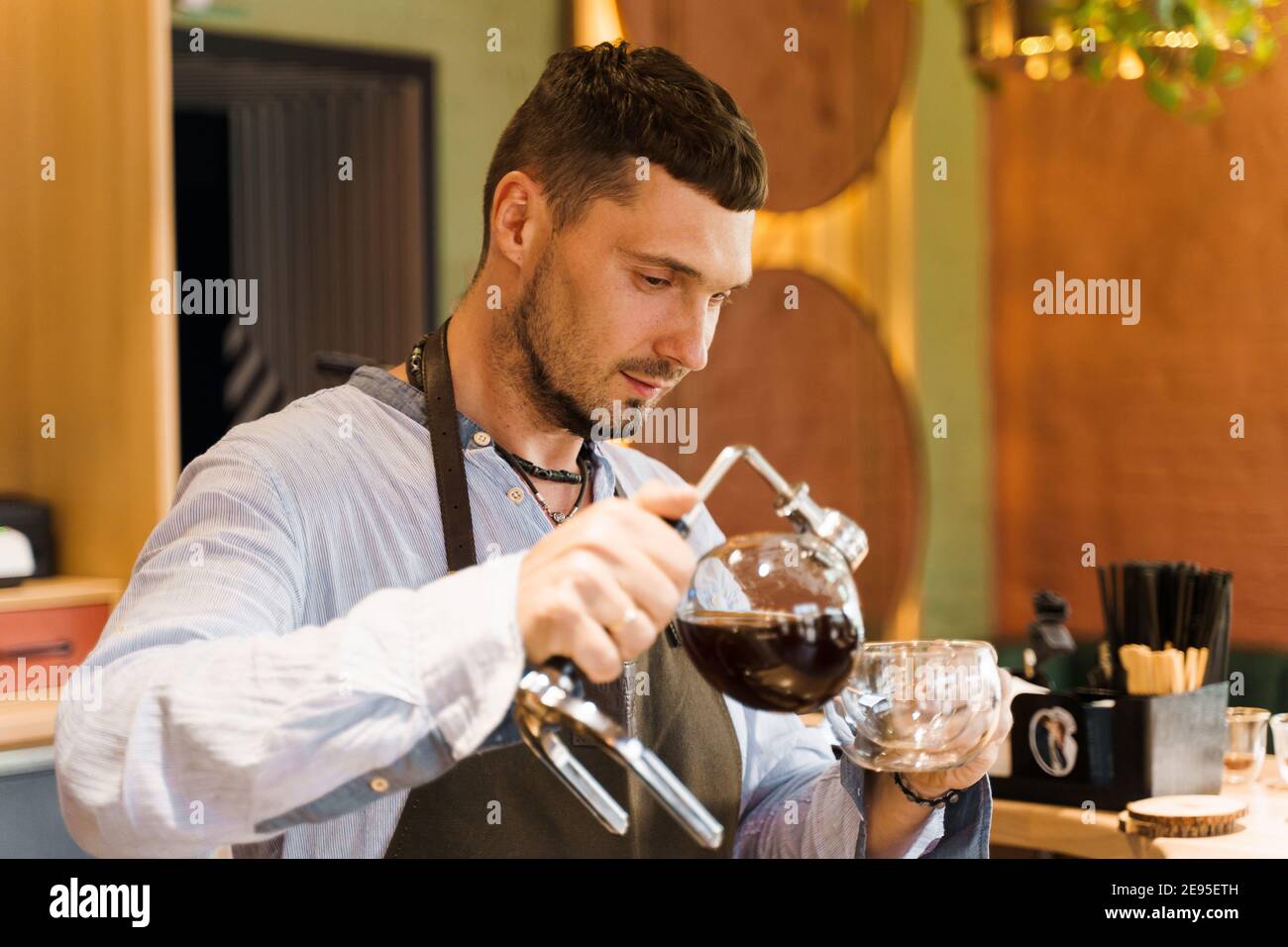 Syphon alternative method of making coffee. Barista pours hot coffee in syphon device for customers. Coffee brewing in cafe. Scandinavian method of co Stock Photo