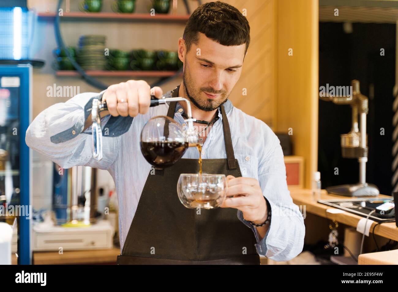 Syphon alternative method of making coffee. Barista pours hot coffee in syphon device for customers. Coffee brewing in cafe. Scandinavian method of co Stock Photo