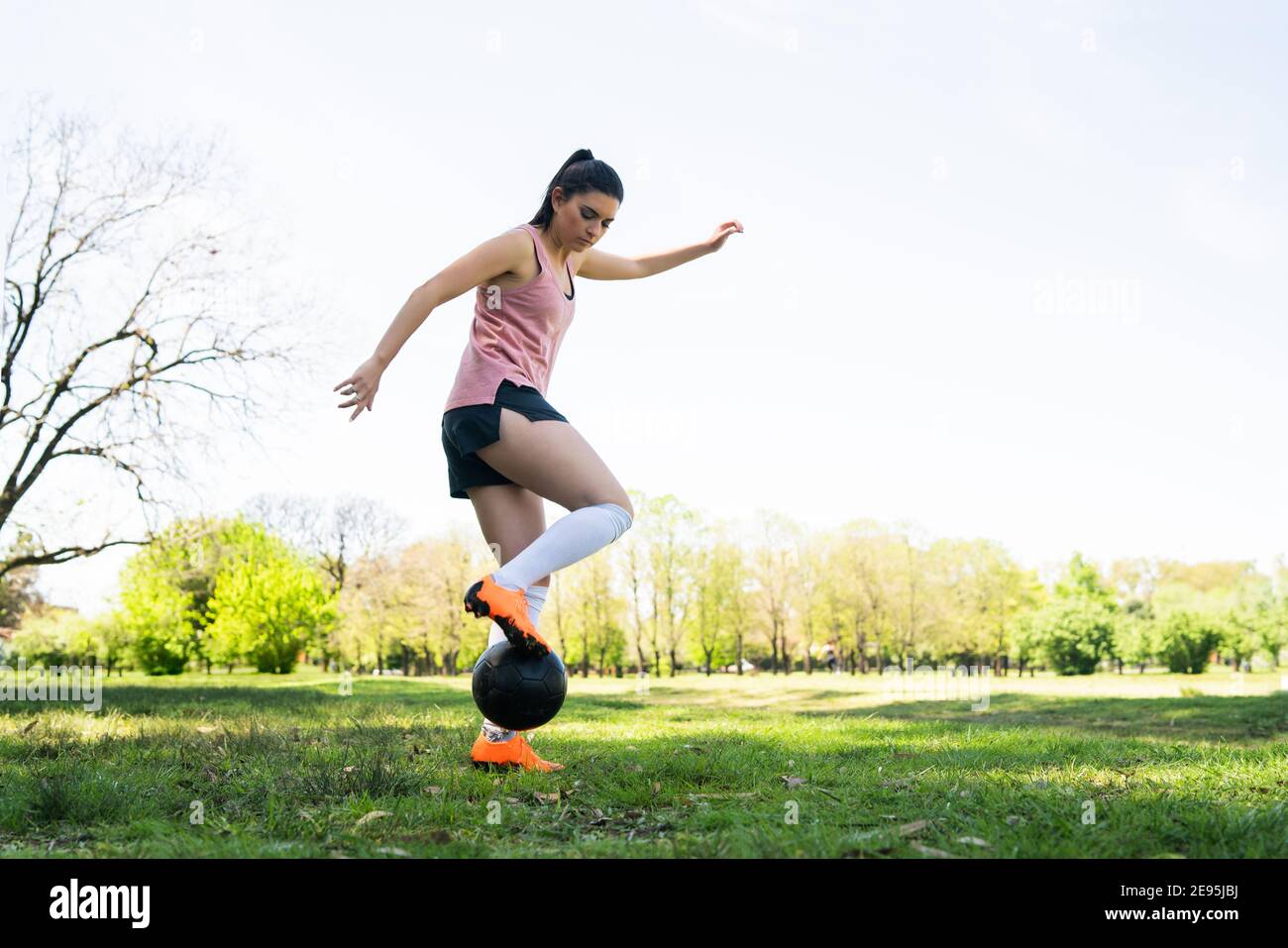 Portrait of young female soccer player running around cones while