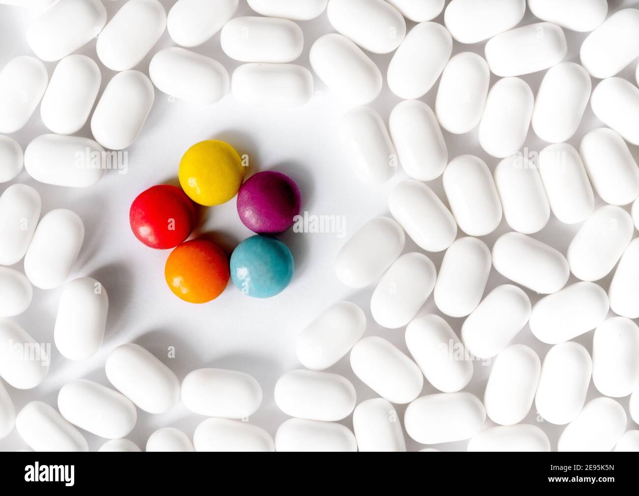 White and bright multi-colored pills on bright white background. The concept of individuality, out the box, non-standard thinking. Personality concept Stock Photo