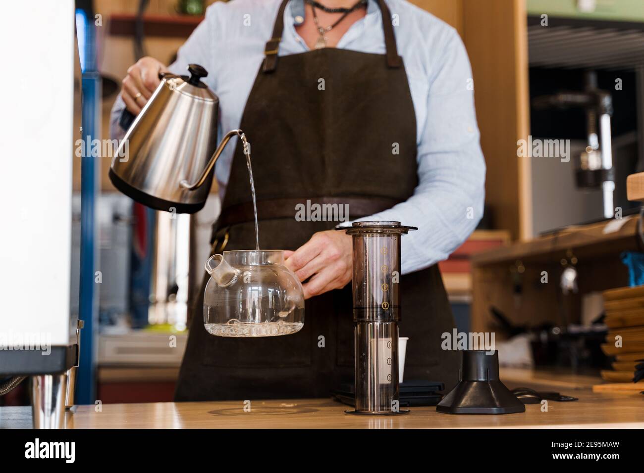 Aeropress coffee alternative making by barista in the cafe. Barista pours hot water in pot for making aeropress coffee with special device. Advert for Stock Photo Alamy