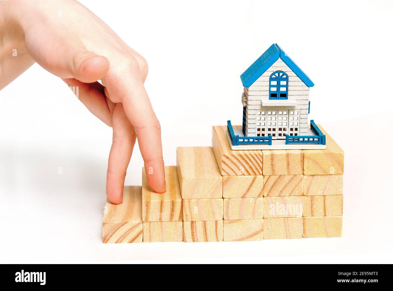 fingers stepping up on wooden blocks to miniature house on wooden board on a white background.The concept of growth in business. financial home loan Stock Photo