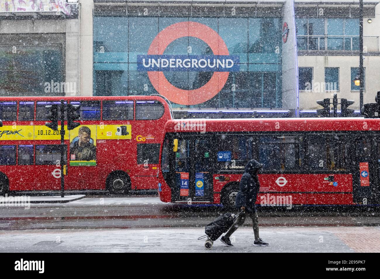 Buses pass outside Brixton Underground Station during heavy snow