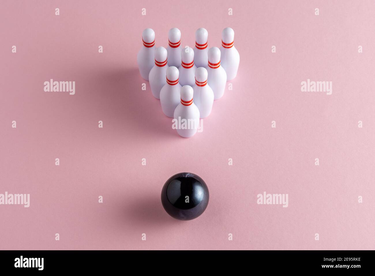 Bowling ball and white skittles on pastel pink background. Minimal creative concept. Stock Photo