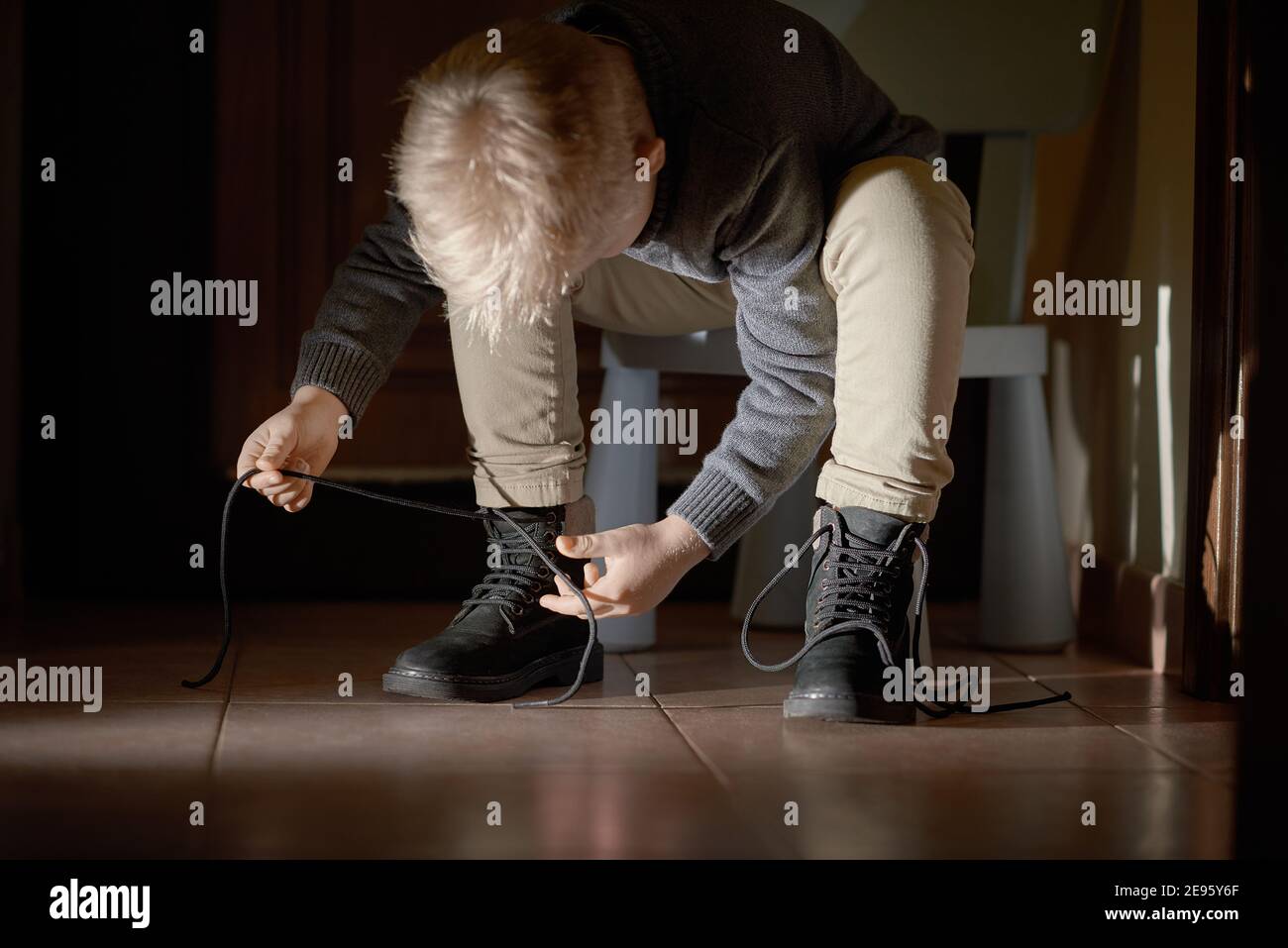 Child tying his shoes before leaving home, selective focus Stock Photo