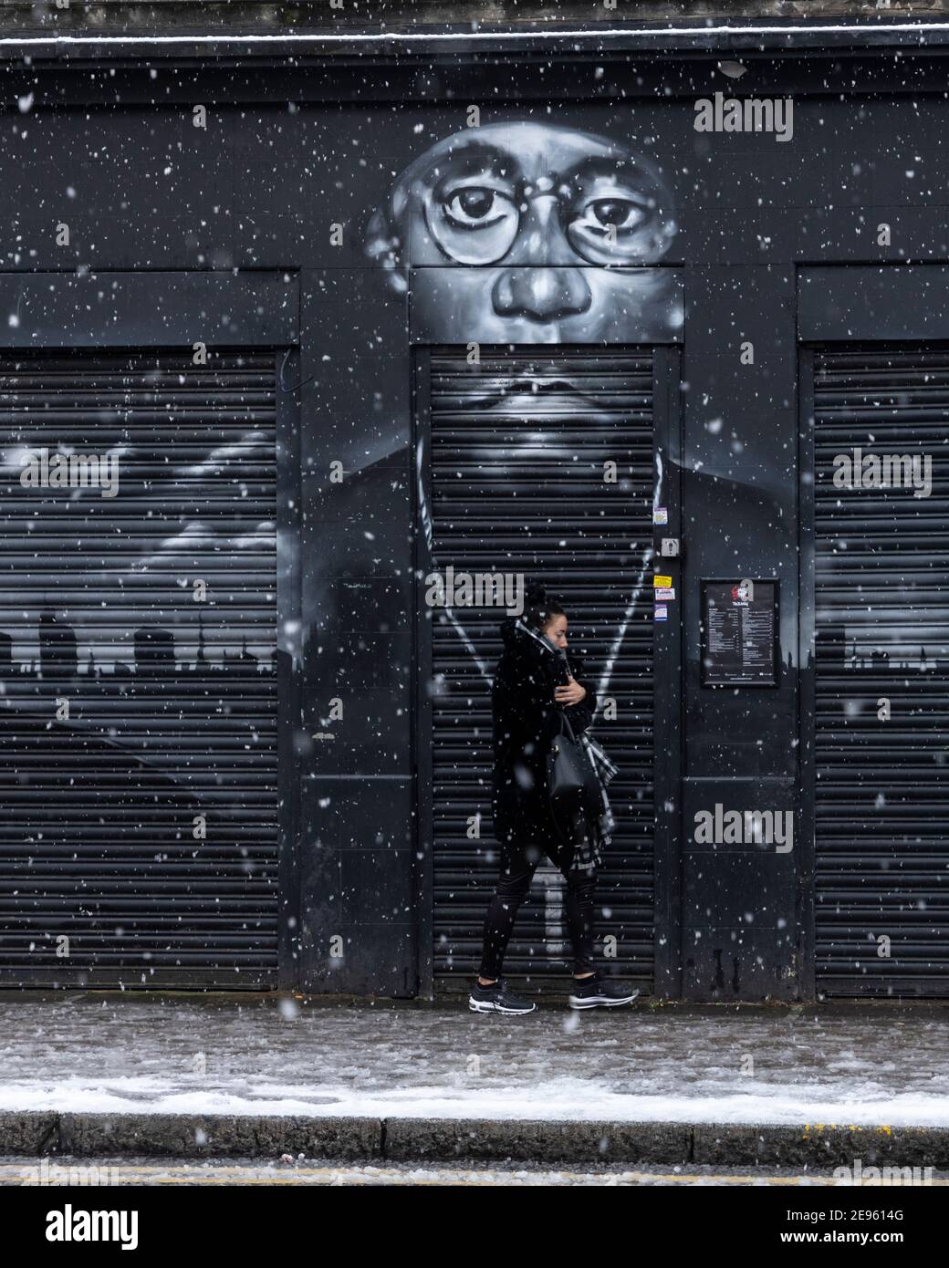 A girl walks past street mural of rapper 'Big L' during heavy snow, Atlantic Road, Brixton, London, 24 January 2021 Stock Photo