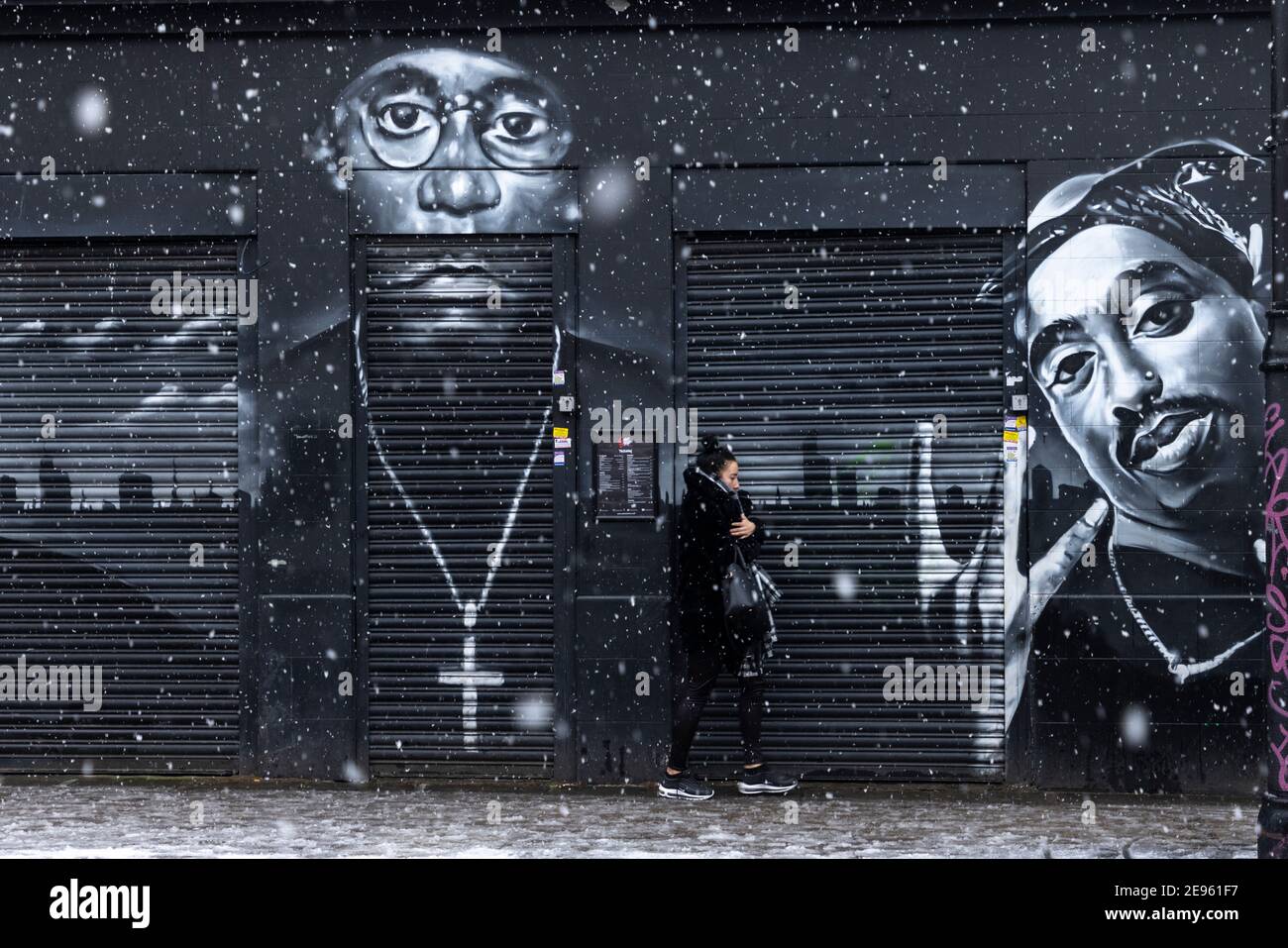 A girl walks past street murals of rappers 'Big L' and '2Pac' during heavy snow, Atlantic Road, Brixton, London, 24 January 2021 Stock Photo