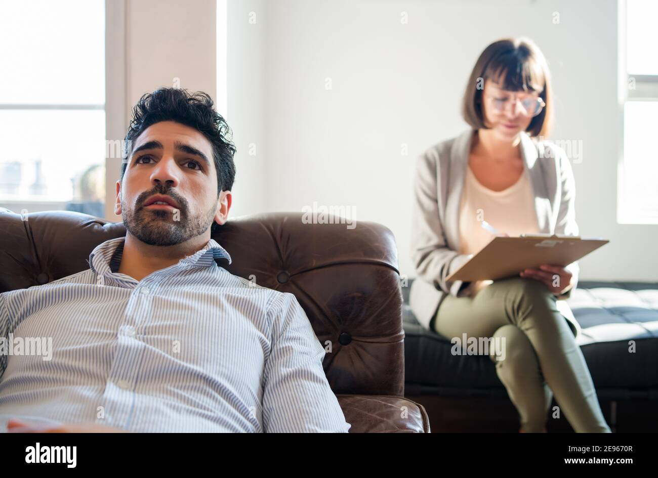 Closeup of a psychologist taking notes on clipboard while her patient