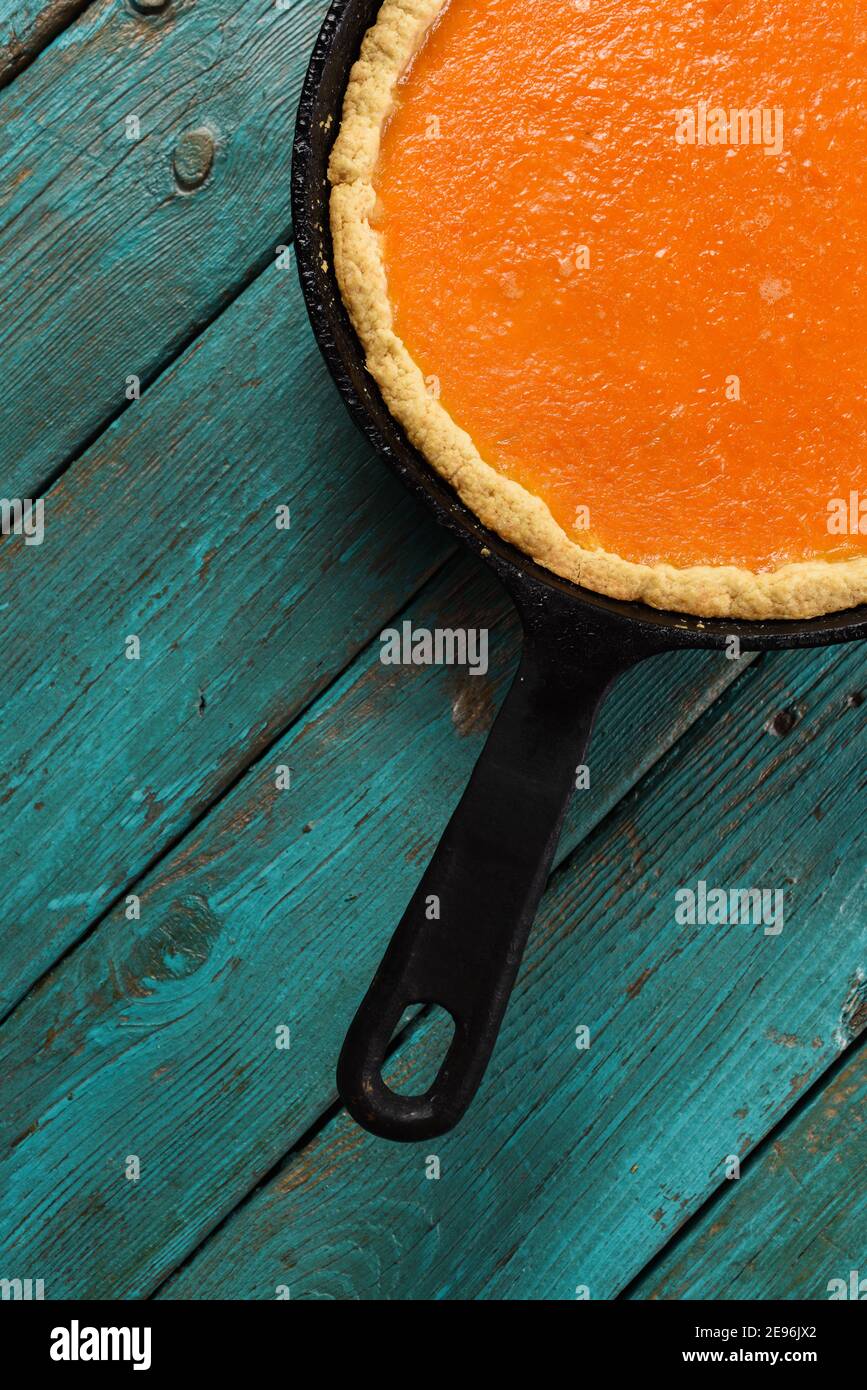 Bright pumpkin pie in cast iron pan on turquoise background minimalist style copyspace Stock Photo