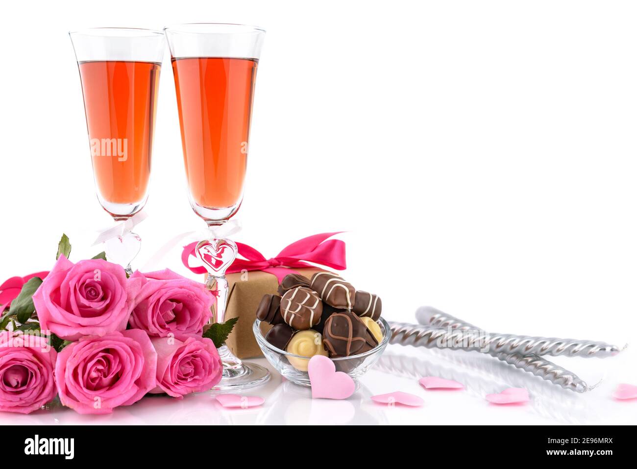 Valentine's Day concept. Two glasses of wine, gift box, candles, pink roses, sponge satin hearts and delicious chocolate pralines on a white backgroun Stock Photo