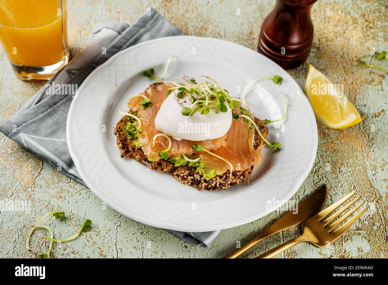 Toast mashed avocado, salmon, poached egg and microgreens Stock Photo