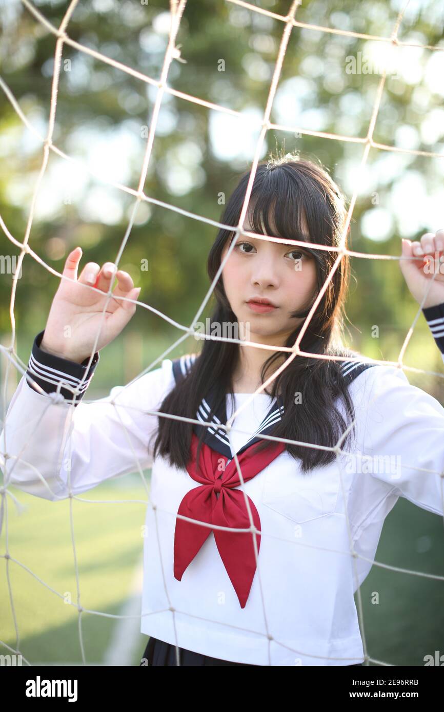 Portrait of Asian japanese high school girl uniform looking with soccer goal nets Stock Photo