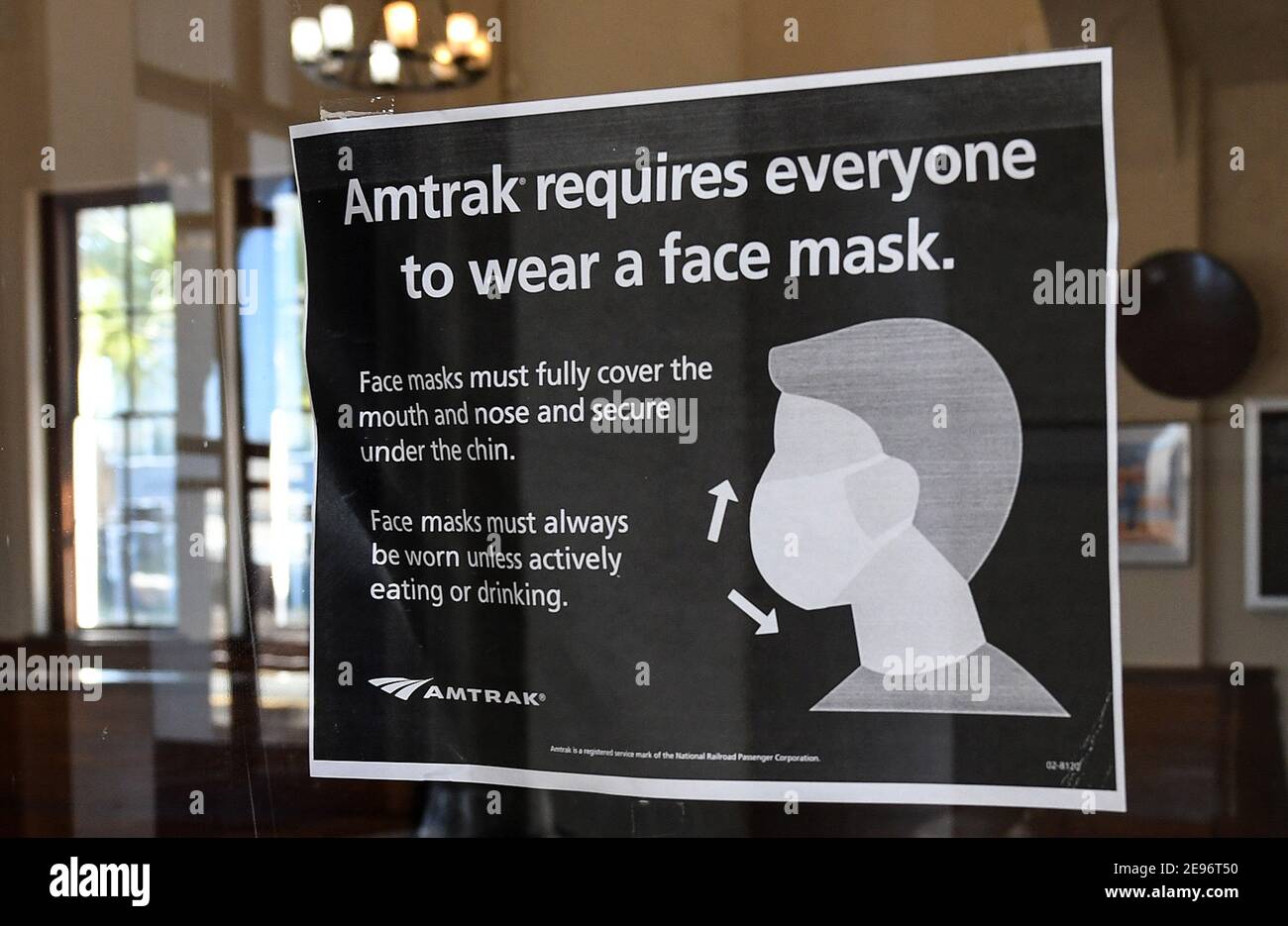 A sign advising passengers of a face mask requirement is seen on a window at the Orlando Amtrak