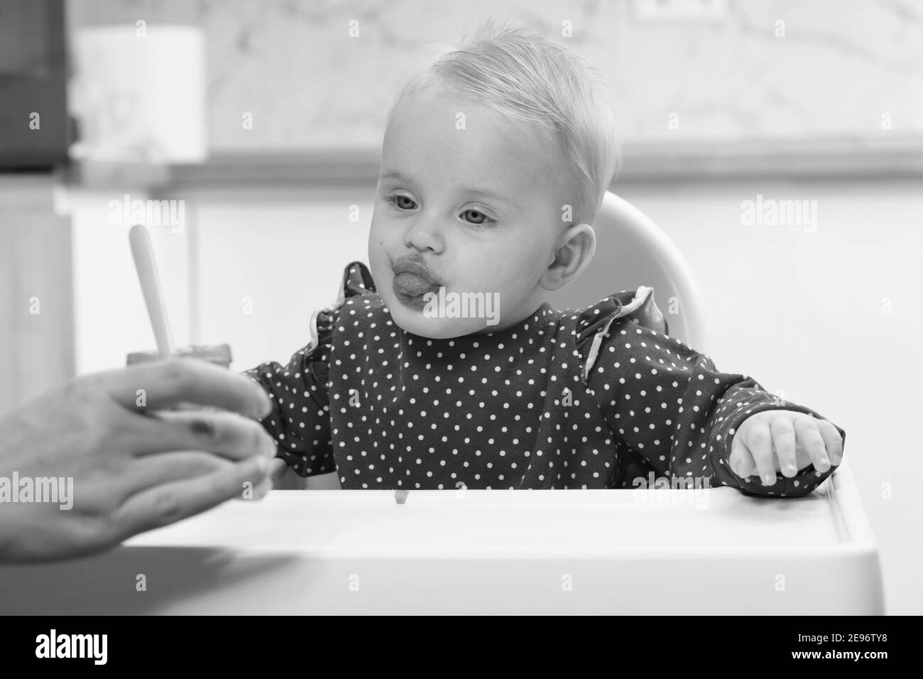 Happy Mother Nanny Or Sister Feeds A Little Baby With A Spoonful Of Food At Home Stock Photo