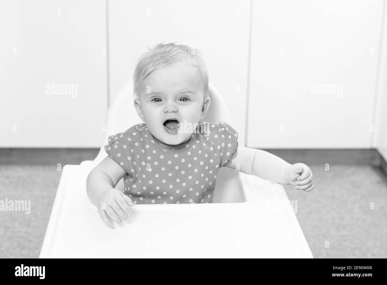 Little Baby Girl Sit on a Chair and Ready to Eat and Looking for Mom Stock Photo