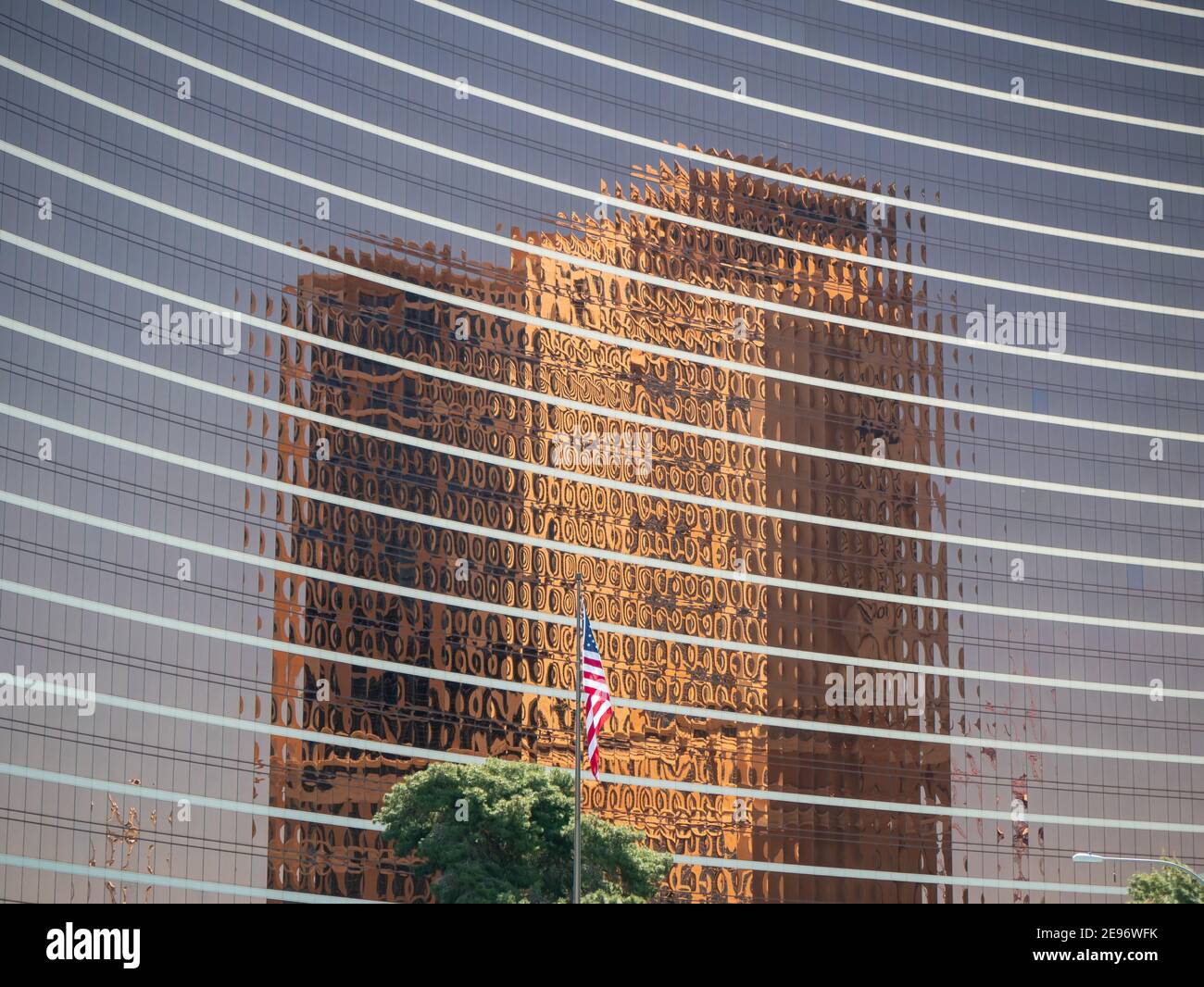 Copper colored high-rise reflecting on another high-rise with American flag Stock Photo