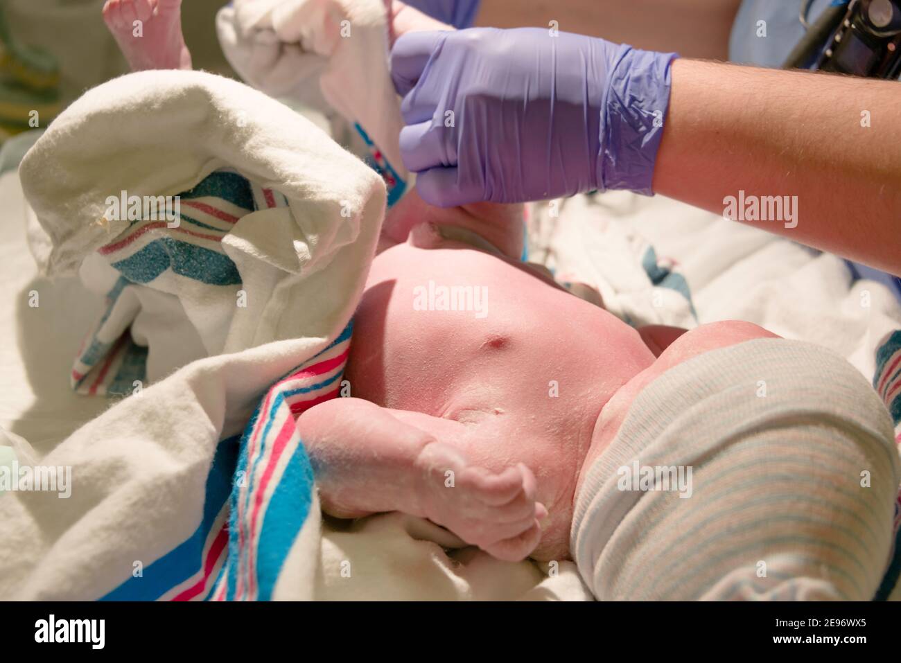 Nurse cleaning newborn baby girl in hospital delivery room. Stock Photo