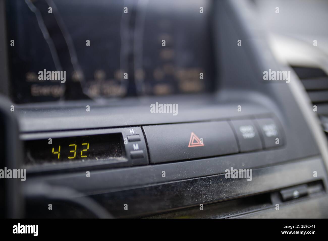 Emergency blinkers button and digital clock on dusty car dashboard