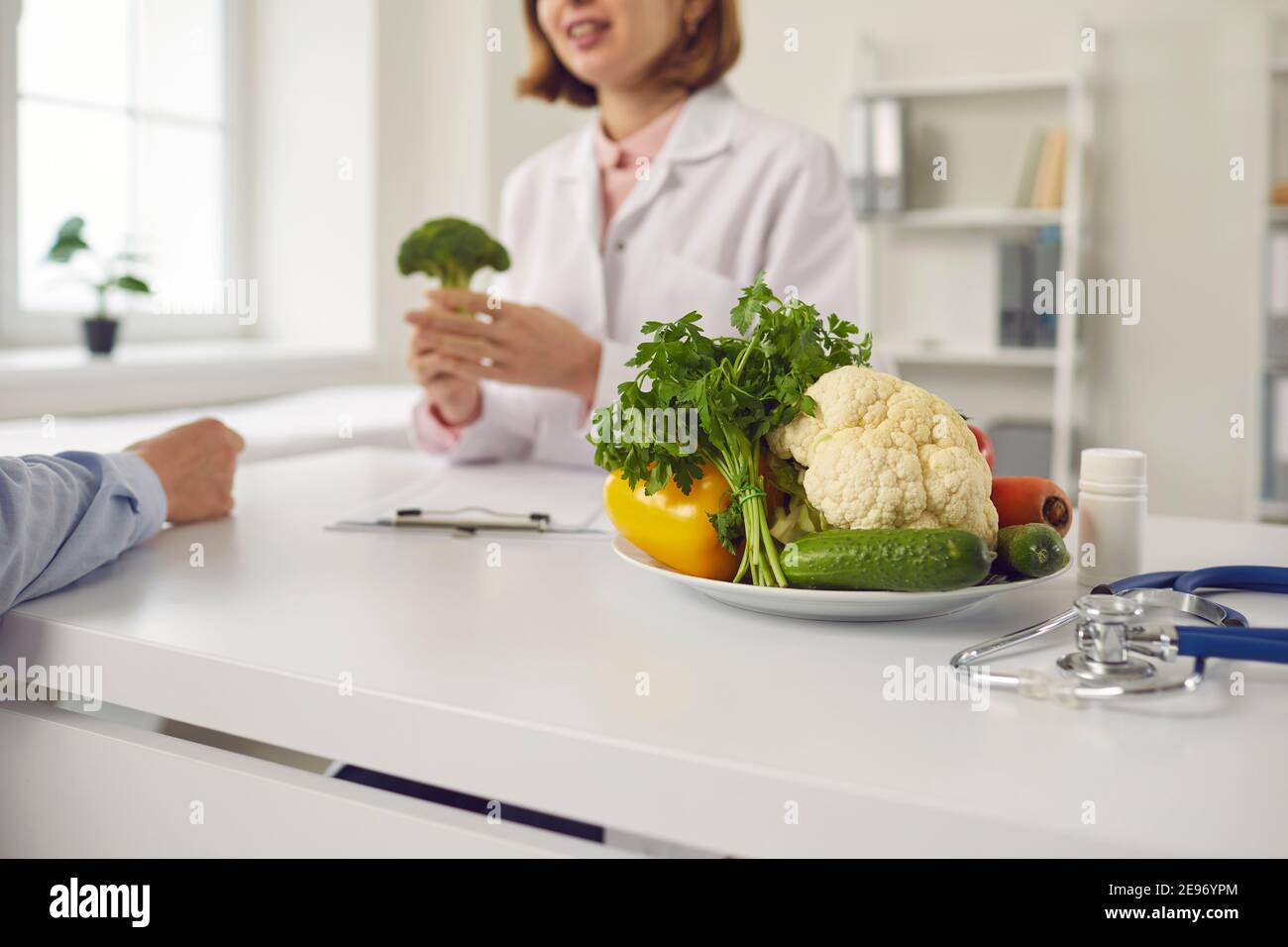Positive woman doctor nutritiologist talking with man patient about benefits of fresh vegan healthy diet Stock Photo