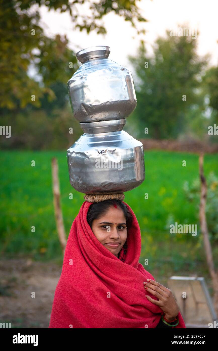 TIKAMGARH, MADHYA PRADESH, INDIA - JANUARY 23, 2021: An Indian woman carrying a container of water on her head. Stock Photo