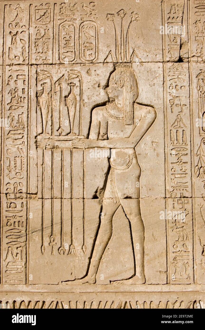 Ancient Egyptian hieroglyphic carving of a priest making an offering to Hapi, the god of the Nile. Shown by the lotus on his head. Outer wall of Dende Stock Photo