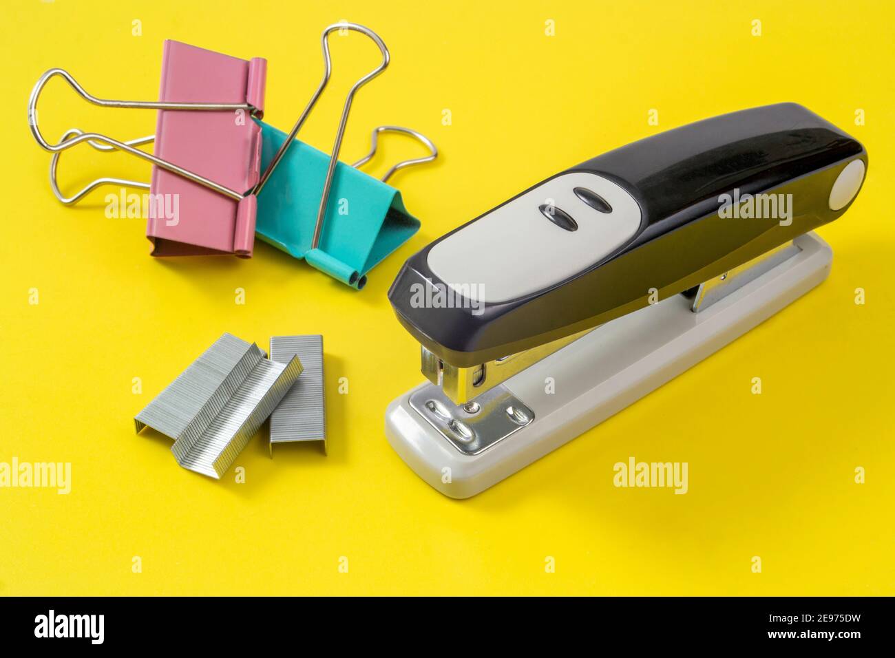 office supplies-stapler, paper clips and clothespins lie on a yellow background Stock Photo