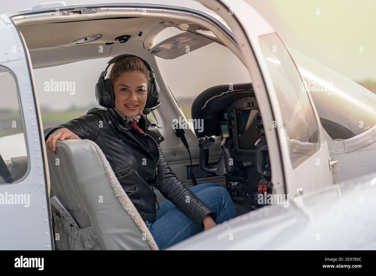 Portrait of Attractive Young Woman Pilot with Headset in Cockpit. Smiling Female Pilot Looking at Camera. Stock Photo
