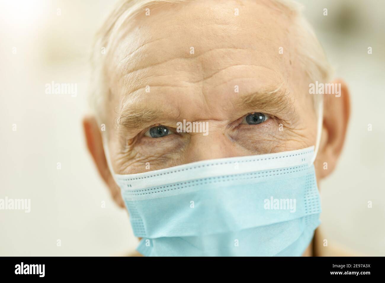 Closeup photo of senior citizen wearing surgical mask while looking at