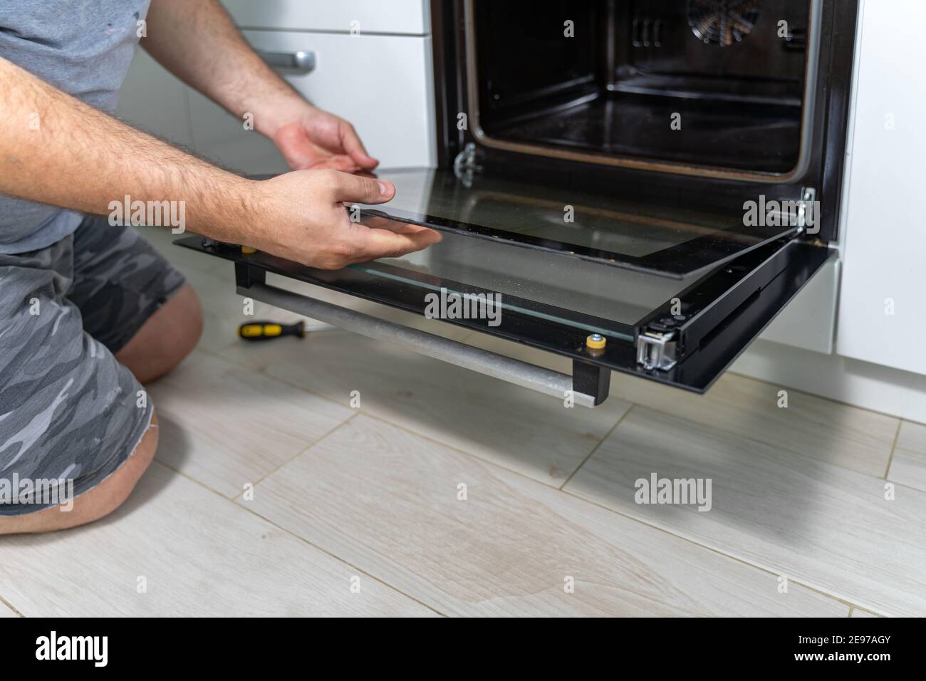 the man removes the fireproof glass from the oven. repair and cleaning of an electric oven Stock Photo