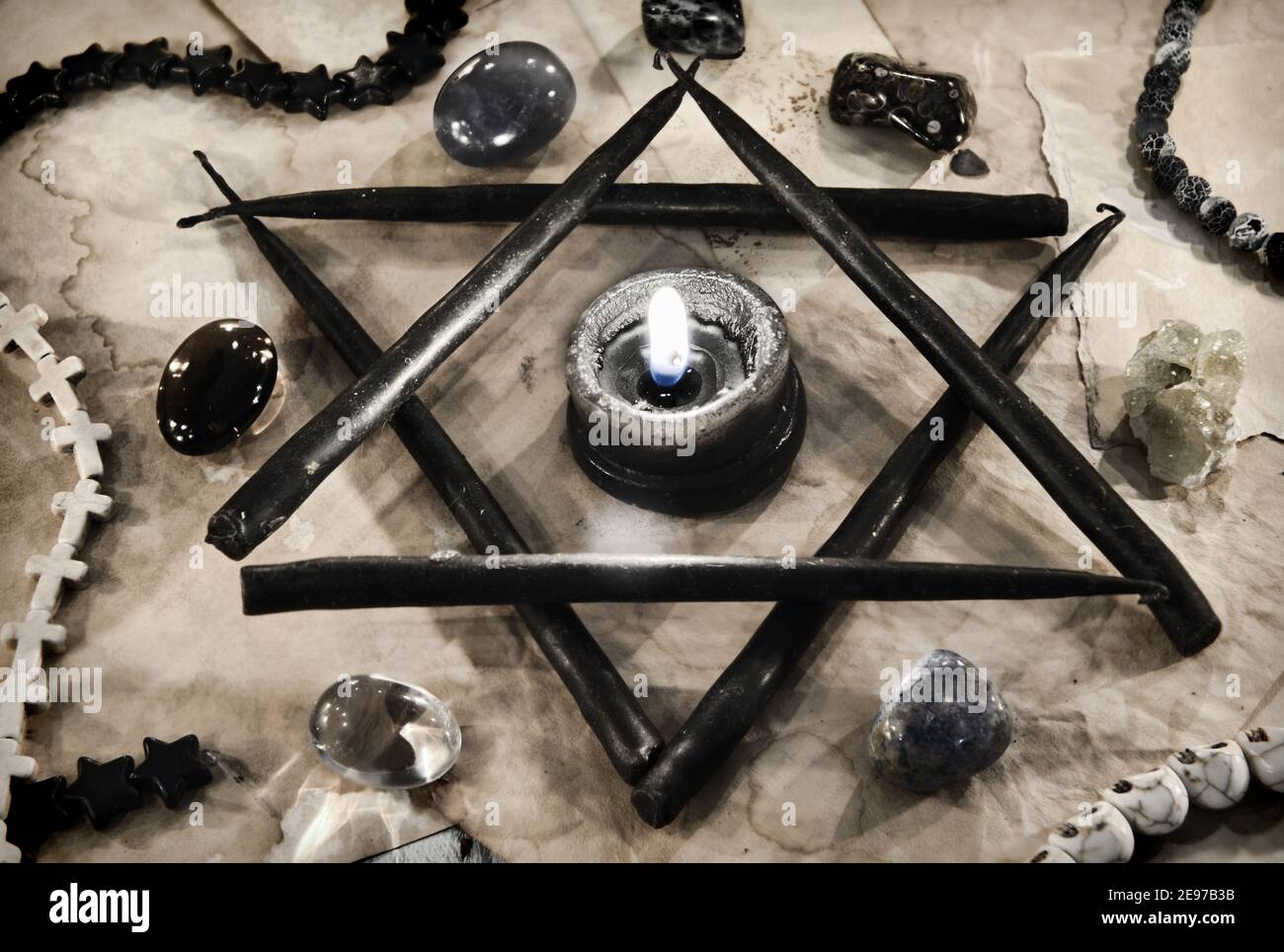 Pentagram symbol made of black candles with crystal stones on paper.  Esoteric, gothic and occult background, Halloween mystic concept. Stock Photo