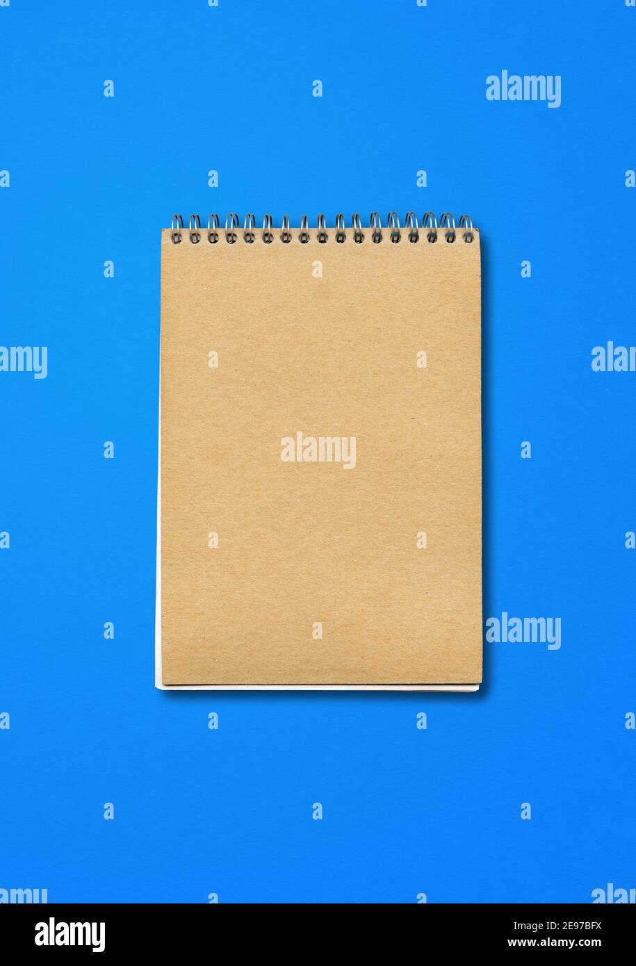 Spiral closed notebook mockup, brown paper cover, isolated on blue