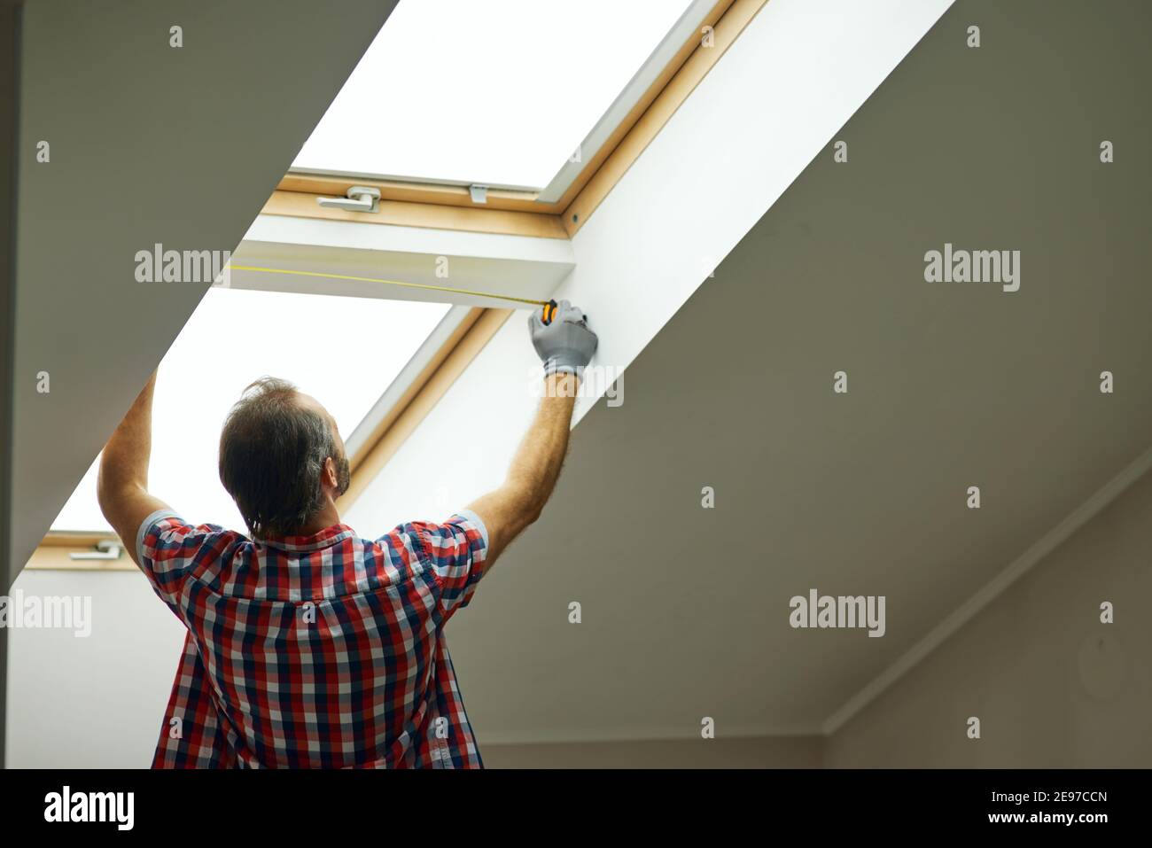 For a better view. Rear view of handyman using measure tape while ...