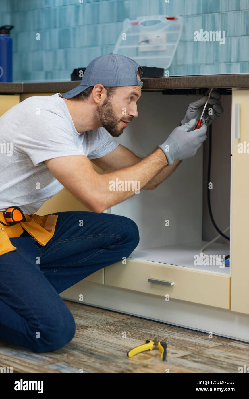 Fixing leaks. Focused young repairman, professional plumber wearing