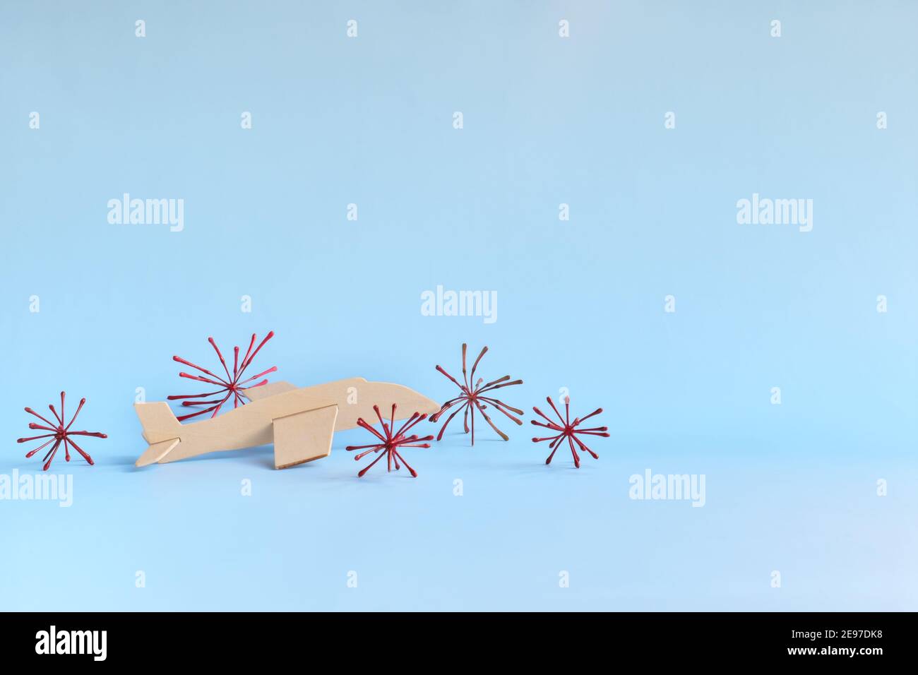 Parked wooden airplane model on sky blue background with coronavirus. Travel ban and cancelled vacation due to covid-19 pandemic concept. Stock Photo