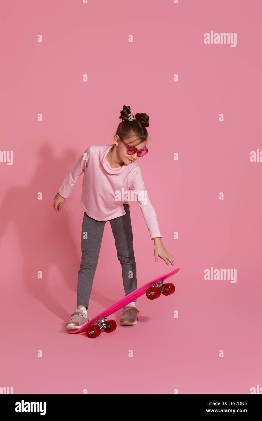 adorable little child girl with pink skateboard in casual clothes on