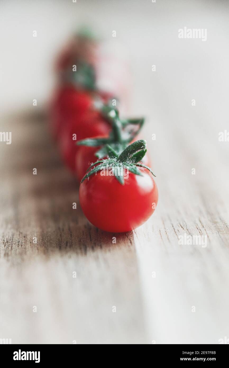 Seven micro tomatoes in a row on a wooden table in The Netherlands Stock Photo