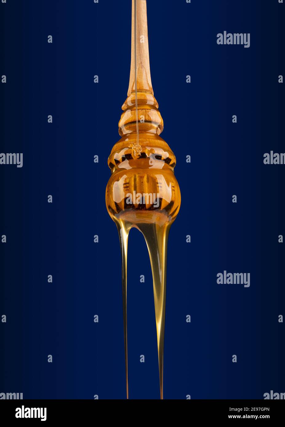 Natural honey dripping of from dripper close viw on blue background. Stock Photo